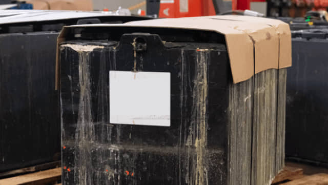 A scrap forklift battery with signs of sulfation on the case