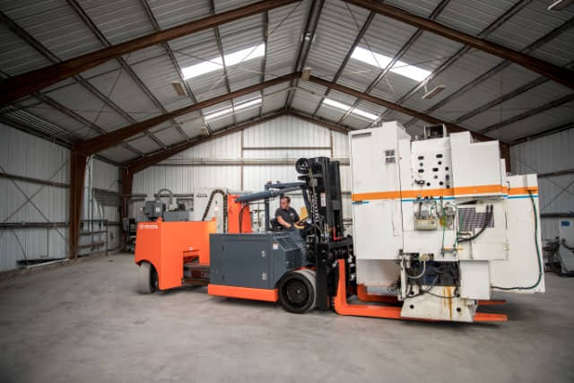 A Toyota adjustable wheelbase heavy-duty forklift lifting a large piece of machinery