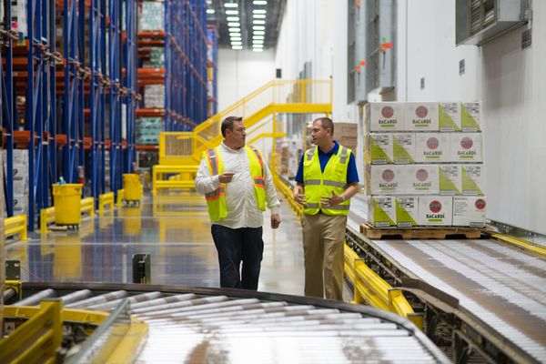 Managers walking and talking in a warehouse near conveyors