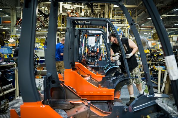 Workers assembling Toyota forklifts chassis' on a manufacturing line