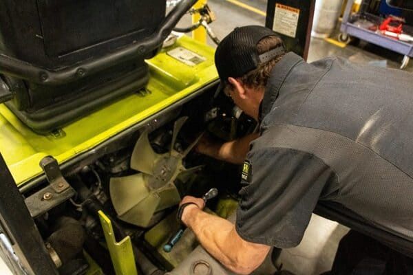 A Conger Industries forklift technician conducting repairs on a CLARK forklift