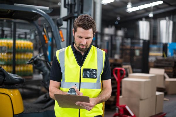 A forklift operator conducting a pre-shift forklift inspection on their clipboard