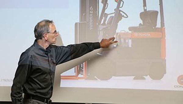 A Conger Industries forklift operator trainer class instructor points to a forklift on a screen