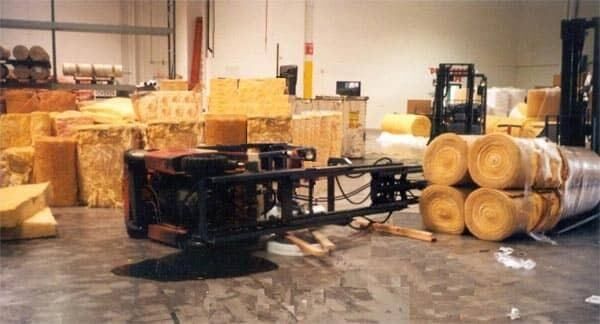 A forklift tipped over inside of a warehouse, spilling rolls of material