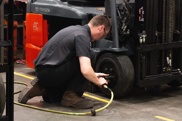 A Conger Industries forklift technician dismounting an electric forklift drive tire