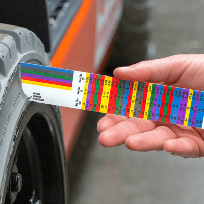 A person using a forklift tire wear indicator to check a forklift tire sidewall