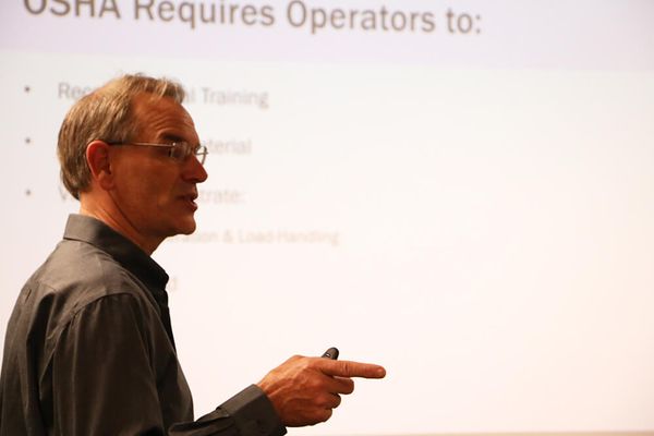 A Conger Industries forklift trainer instructor giving a lecture in front of a PowerPoint screen in class