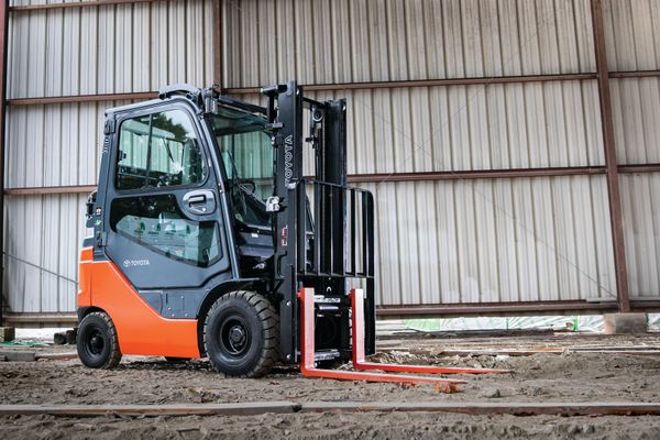 pneumatic-forklift-tire-applications-conger-industries A Toyota pneumatic forklift with a cab and pneumatic tires parked on dirt in an outdoor warehouse