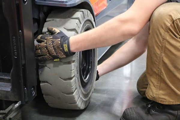pneumatic-to-solid-forklift-tire-conversion-conger-industries A Conger Industries forklift tire technician removing a solid forklift drive tire from the axle