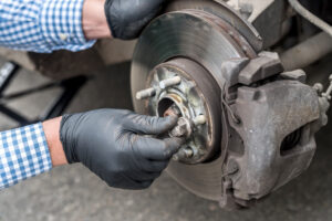 Hands of mechanic repairing brake disk