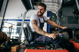 Smiling bearded hardworking employee in a forklift