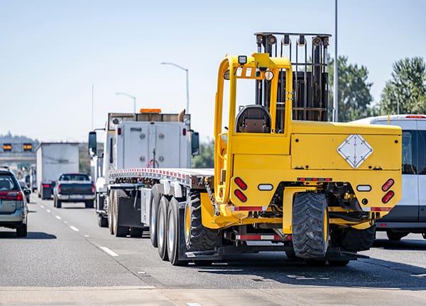 Portable, self-propelled rough terrain forklift on the back of a carrier